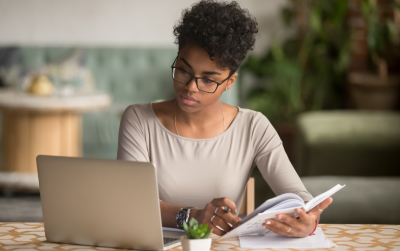 Young woman taking notes for Amazon product research, analyzing data on her laptop.